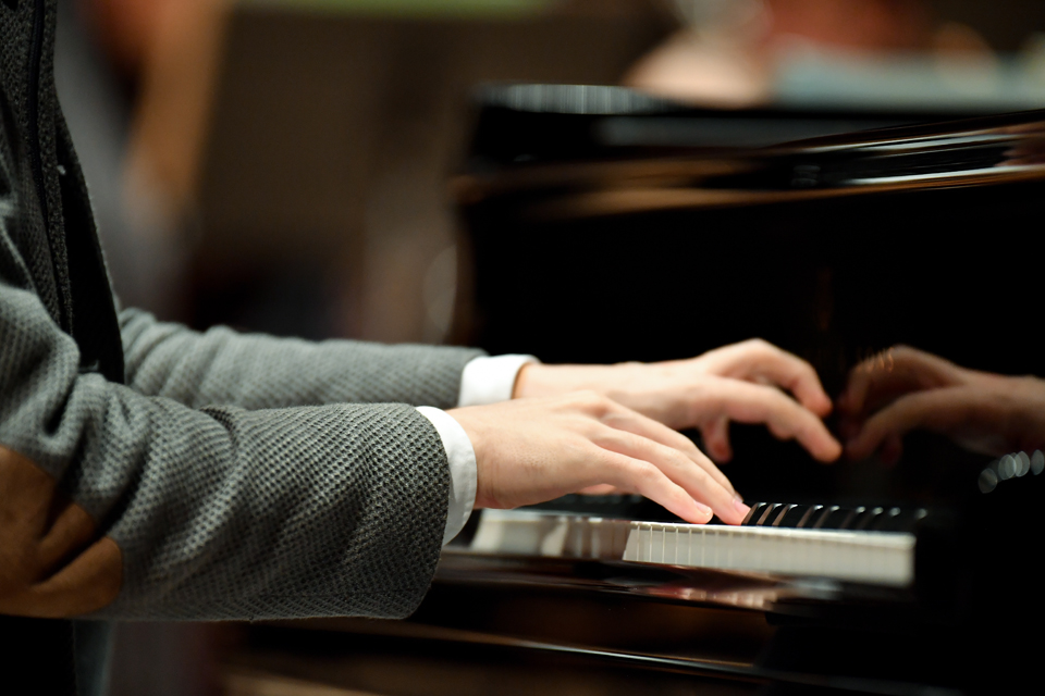 A close-up photo of a performer's hands whilst playing the piano