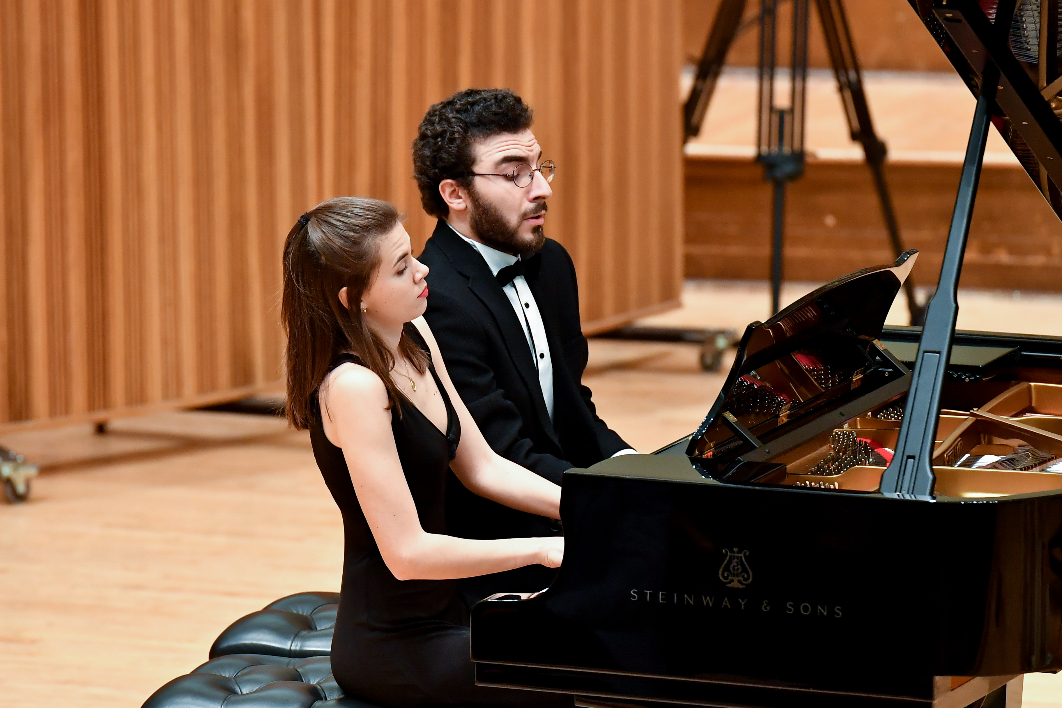A man and a woman sitting at the piano performing a duet 