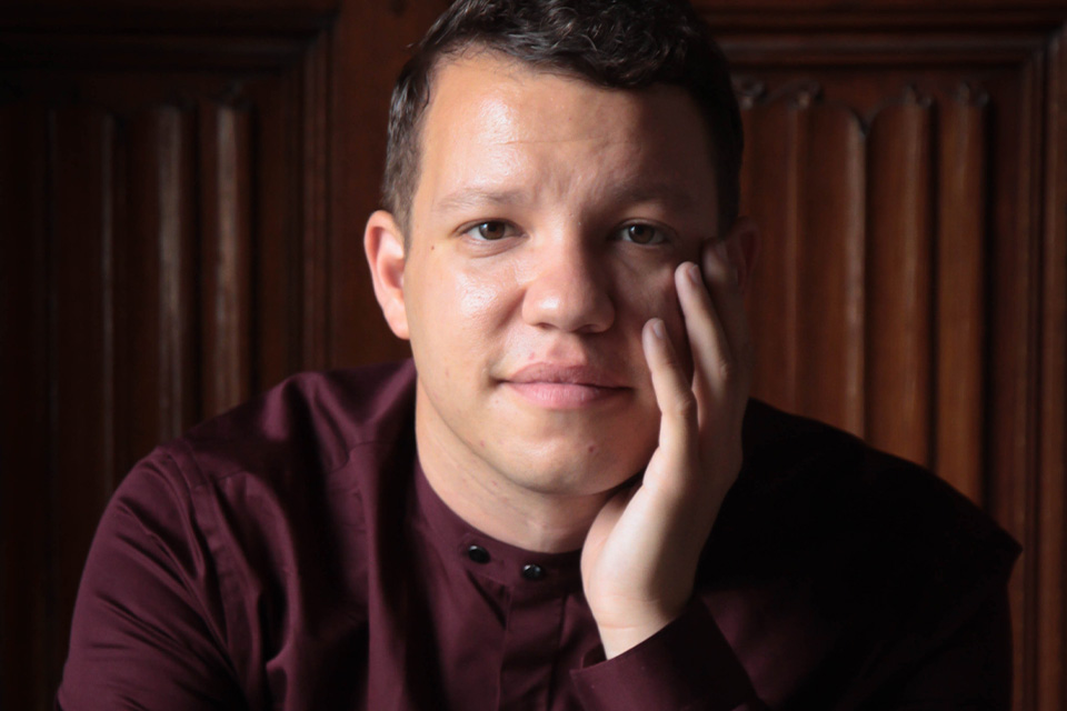 Ryan Bancroft wears a burgundy shirt and rests his hand on his chin