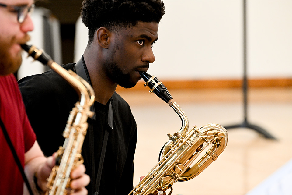 A young man plays the saxophone