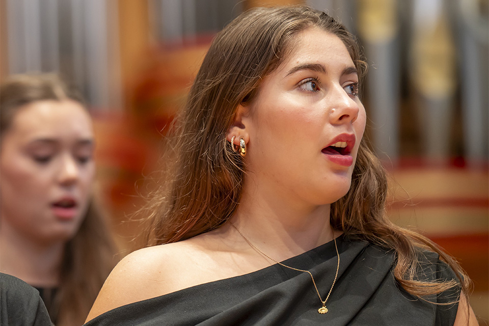 A singer wears black and performs on stage as part of a choir