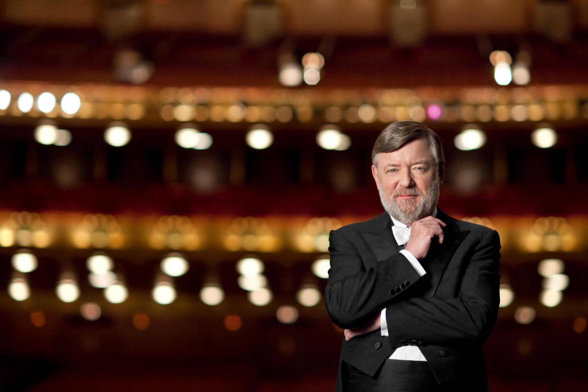 An image of Sir Andrew Davis in a concert hall slightly smiling and looking at the camera