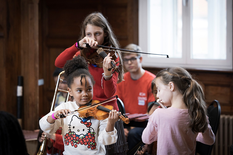 Two young girls smile as they play the violin