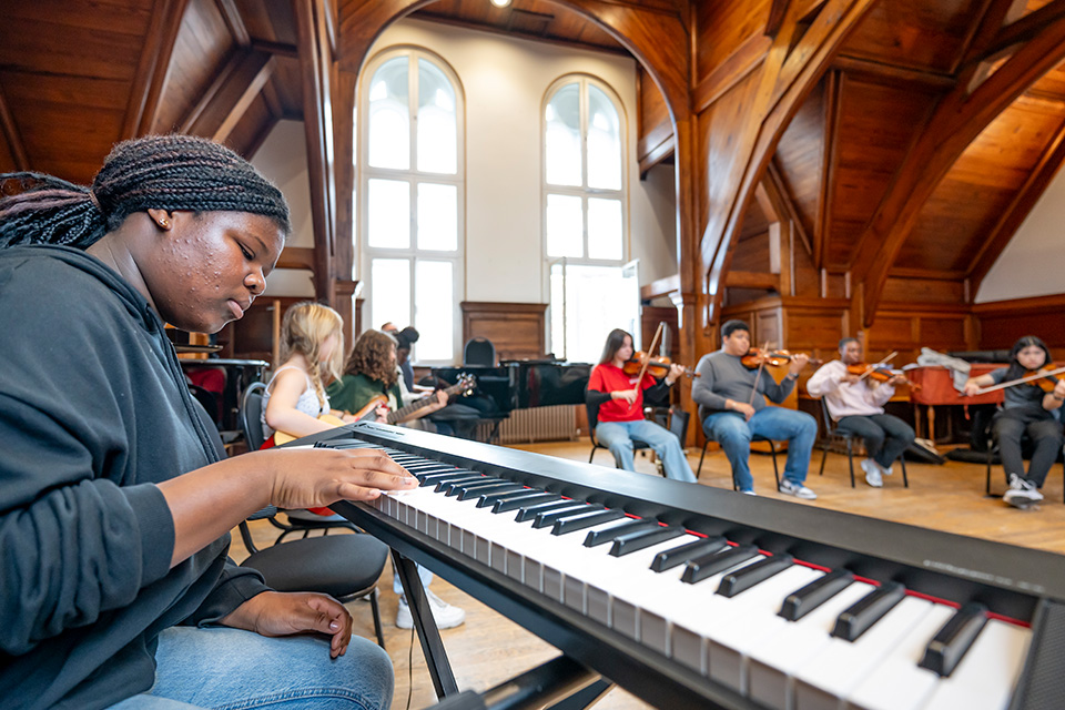 A young girl plays the piano in a group