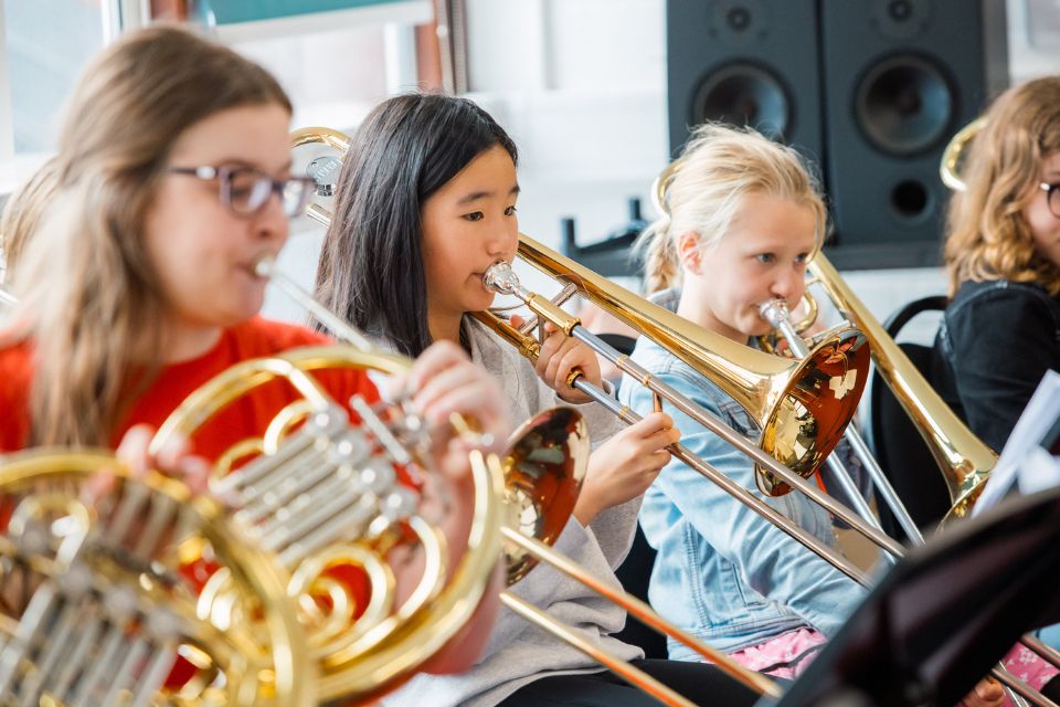 Three young girls play trombones