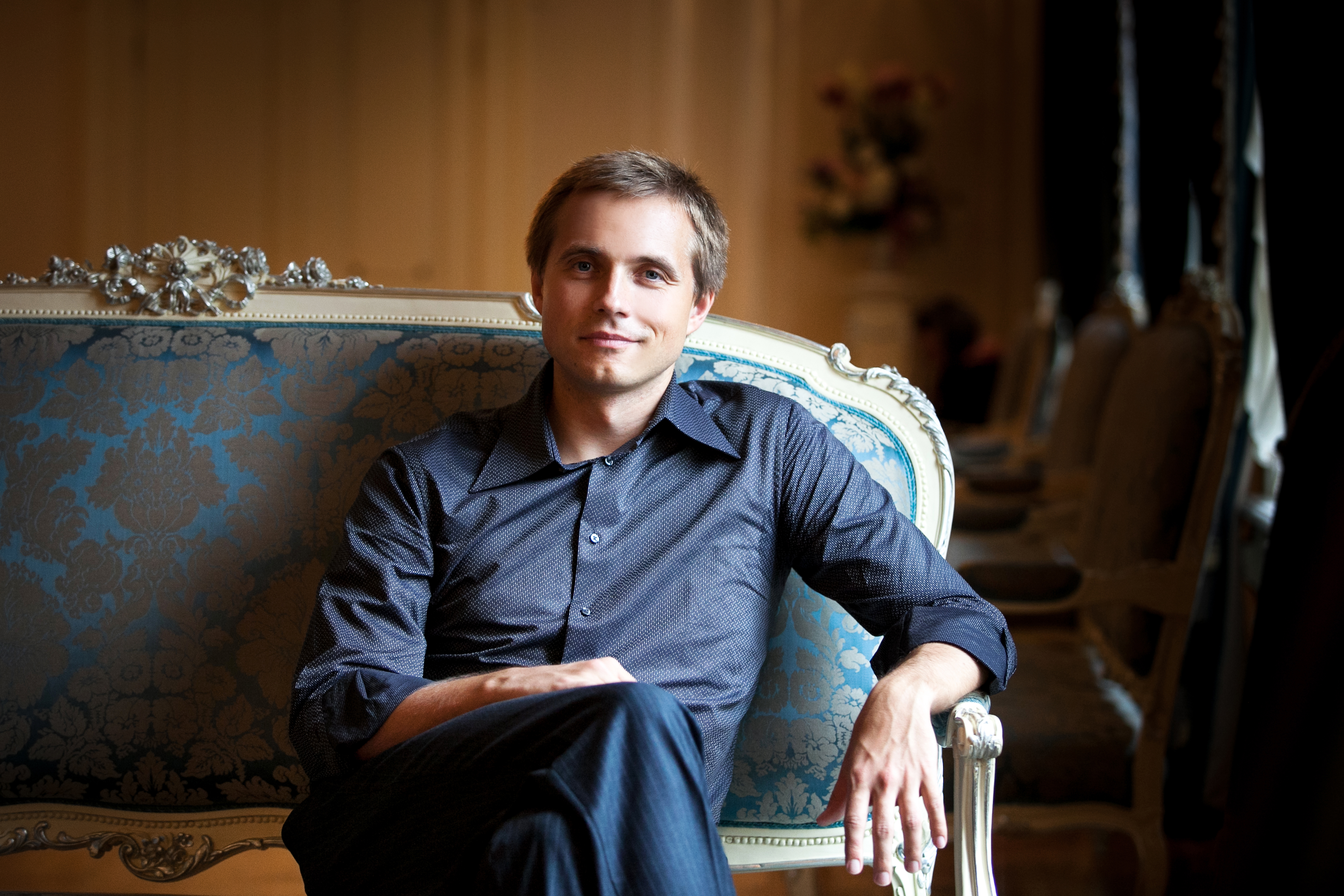 Vasily Petrenko smiling, sitting on an ornate sofa