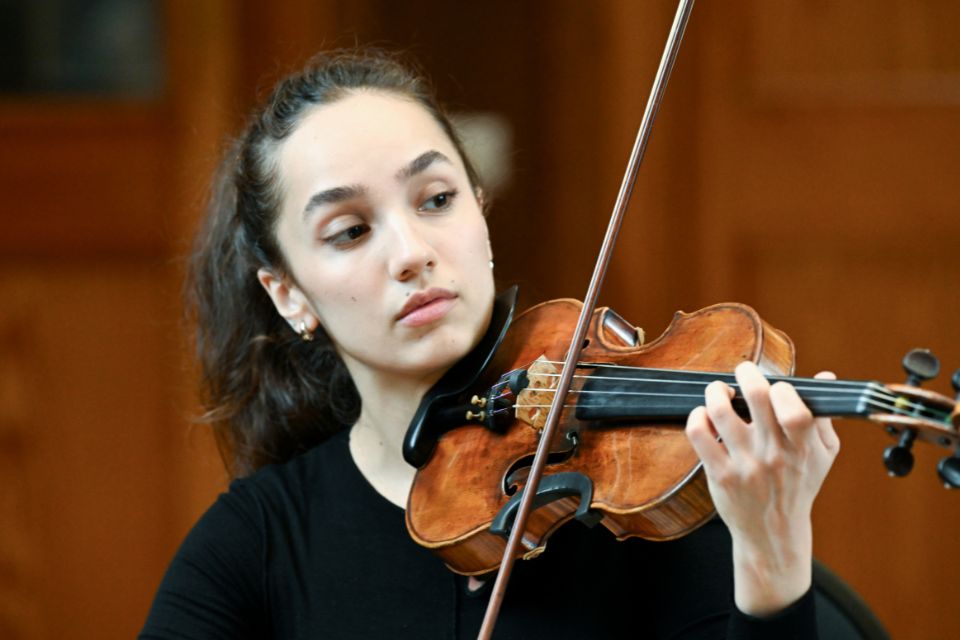 A violinist wears black and plays her instrument passionately