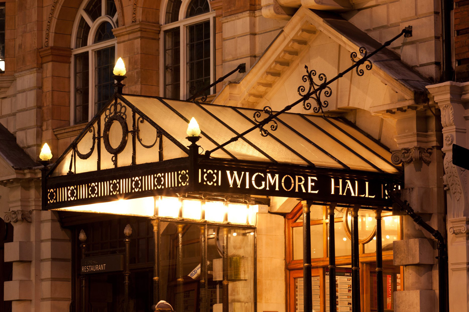 The exterior of the Wigmore Hall entrance hall at night time against a warm glow