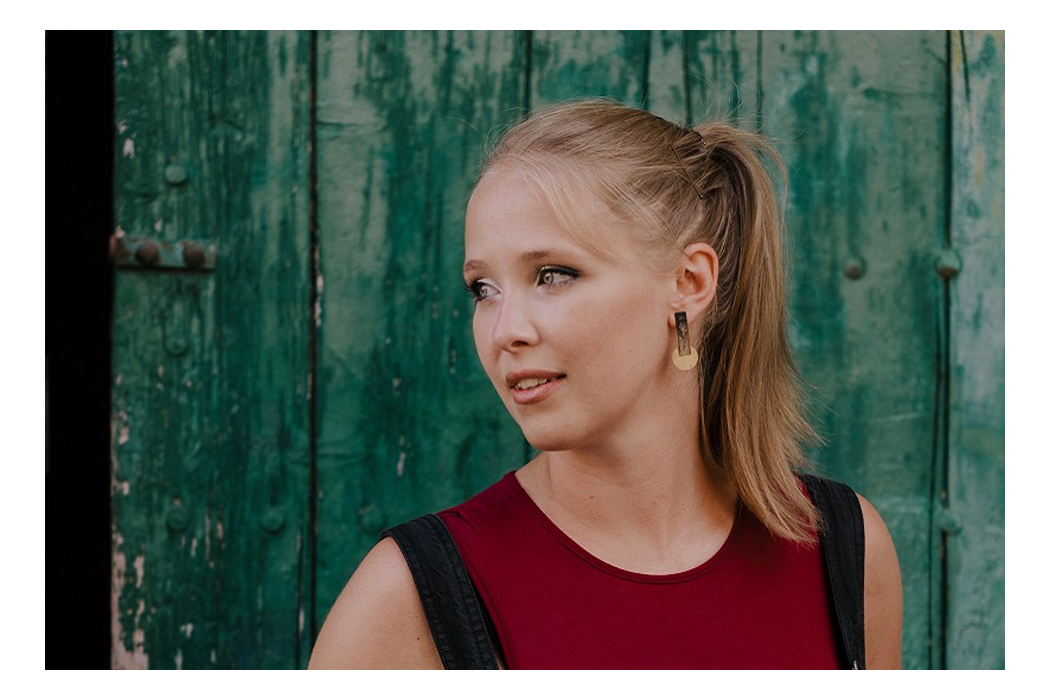 Portrait photo of female alumna in front of a green door, looking away from the camera.