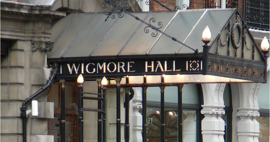 xEntrance of the performance venue Wigmore Hall; the name appears lit from the inside in yellow on the black steel decorated shade at the entrance.